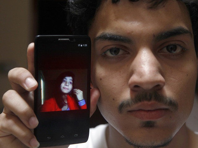 A Pakistan Hassan Khan shows the picture of his wife Zeenat Rafiq, who was burned alive by