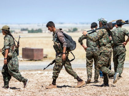 Kurdish People's Protection Units (YPG) fighters walk with their weapons at the eastern entrances to the town of Tal Abyad in the northern Raqqa countryside, Syria, June 14, 2015, after taking control of nearby Suluk town from Islamic State fighters. REUTERS/RODI SAID