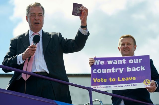 UKIP leader Nigel Farage (L) holds aloft a British passport as he rallies support for the