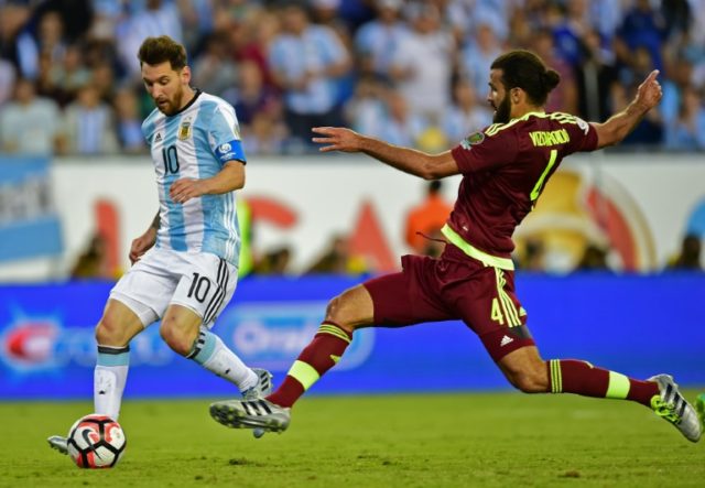 Argentina's Lionel Messi (L) fights for the ball with Venezuela's Oswaldo Vizcarrondo duri