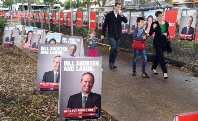 People walk past posters of Australian Labor Party leader Bill Shorten at the launch of th