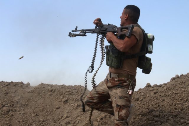 A member of the Iraqi pro-governement forces fires his weapon from the front line in the A