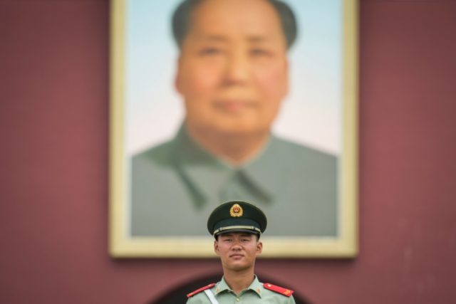 A Chinese paramilitary guard stands in Tiananmen Square under portrait of Mao Zedong in Be