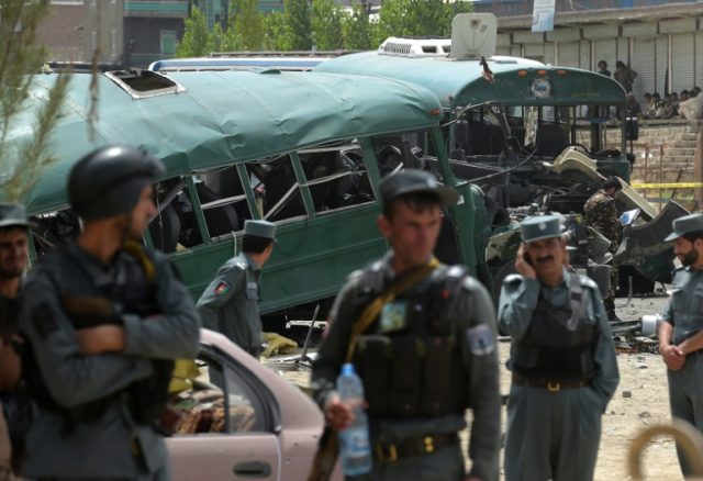 Afghan security personnel gather near the wreckage of buses which were carrying police cad