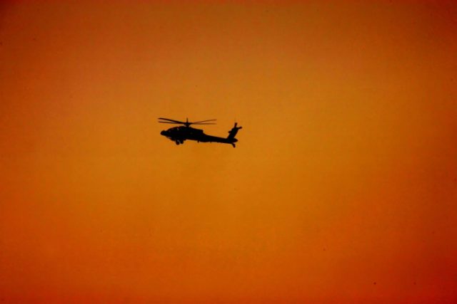 A military helicopter flies over the desert at Al-Hamra military camp, west of the Gulf em
