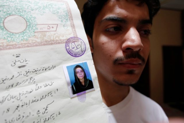 Hassan Khan shows a document with a photograph of his wife Zeenat Bibi, who was burnt aliv