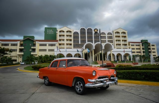 A vintage car passes in front of the Four Points by Sheraton hotel in Havana, the first ad