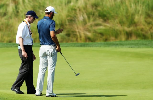Dustin Johnson chats with a rules official on the fifth green during the final round of th