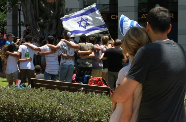 An Israeli couple looks towards people gathering at a restaurant which was targeted by Pal