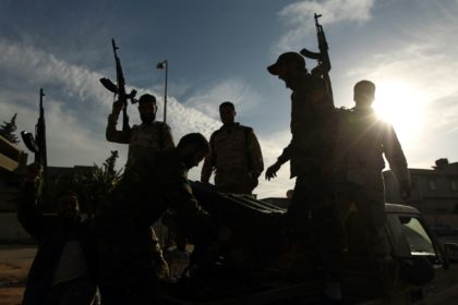 Members of a brigade loyal to General Khalifa Haftar hold up their guns in the eastern Lib