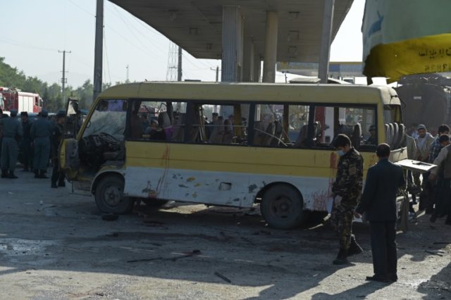 Afghan policemen look at the site of a suicide attack to have hit a minibus carrying forei