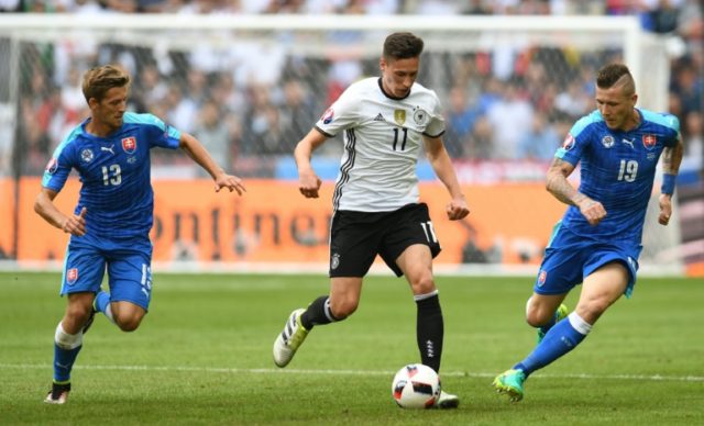 Germany's midfielder Julian Draxler (C) moves the ball down the pitch past Slovakian midfi