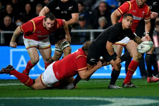 New Zealand's Aaron Smith (R) gets a pass away as he is tackled by Tomas Francis of Wales