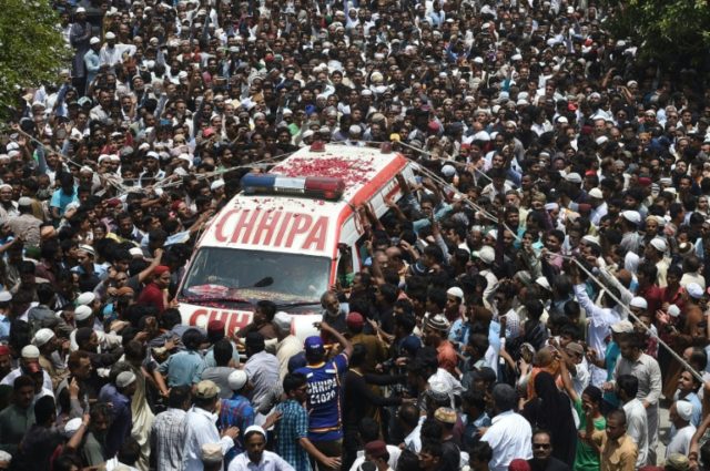 Pakistani mourners gather around an ambulance carrying the coffin of Sufi musician Amjad S