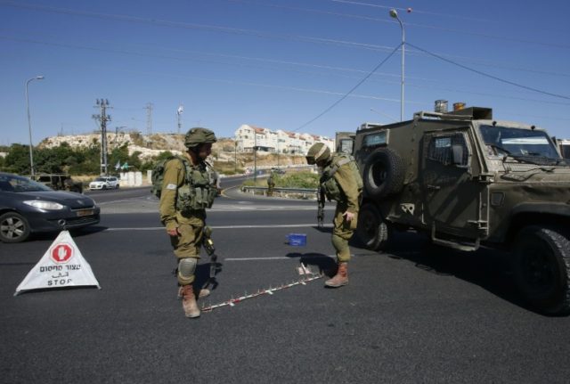 Israeli soldiers set up a checkpoint on the road near the Jewish West Bank settlement of K