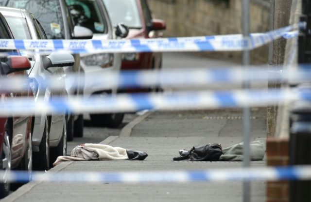 Police crime scene tape surrounds a shoe and handbag lying on the ground outside the libra