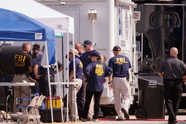Law enforcement officials, including members of the Federal Bureau of Investigation, work