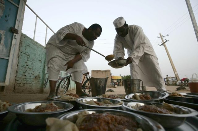 Sudanese men prepare food before an Iftar dinner by the side of the Khartoum highway in th