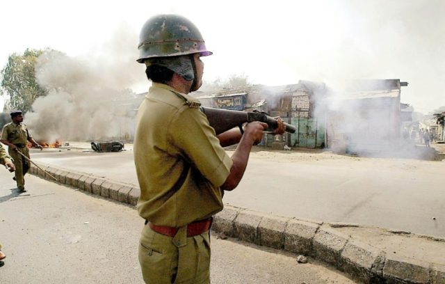 Riot police fire tear gas to disperse a Hindu mob that attacked a mosque in Ahmedabad in G