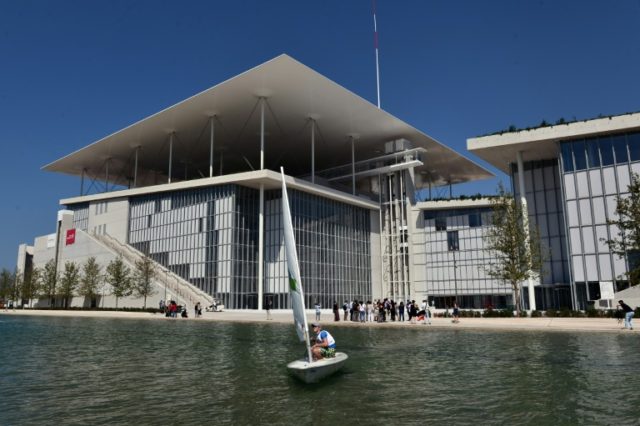 A man sails in front of the newly built Athens national Opera (L) and library buildings at