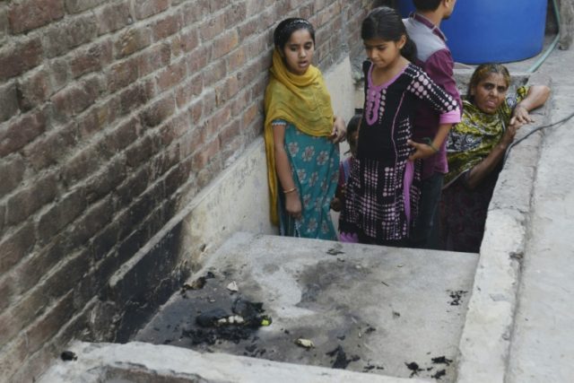 Pakistanis stand at the site where a teenager was burnt alive by her mother in Lahore on J