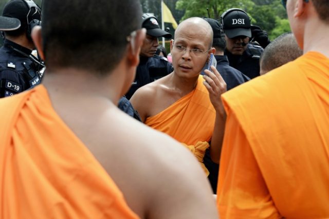 A monk from the controversial Dhammakaya temple talks on the phone as he is surrounded by