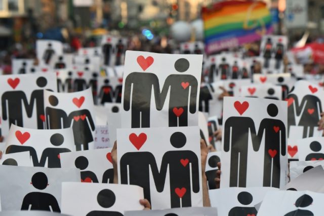 People hold placards depicting hearts and couples, during a flash mob for the annual Lesbi