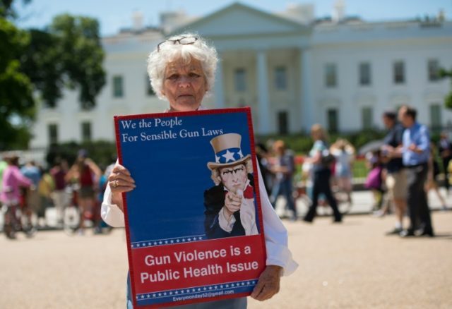 A woman walks with a sign to protest gun violence and call for sensible gun laws outside t