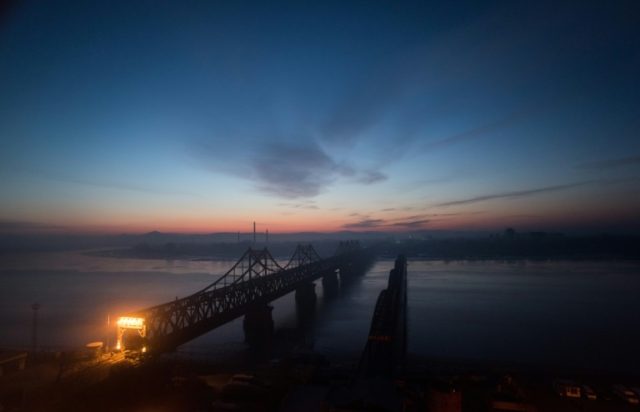 The sun rises over the bridge on the banks of the Yalu River in the Chinese border town of