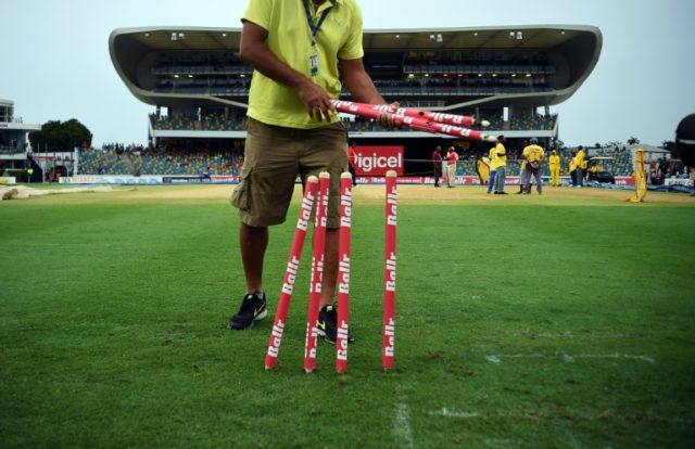 A man collects the stumps from the field after rain interrupted at the Kensington Oval sta