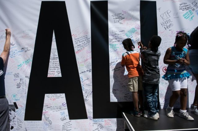 People leave notes on an "I Am Ali" banner outside the Performing Arts Center to honor box