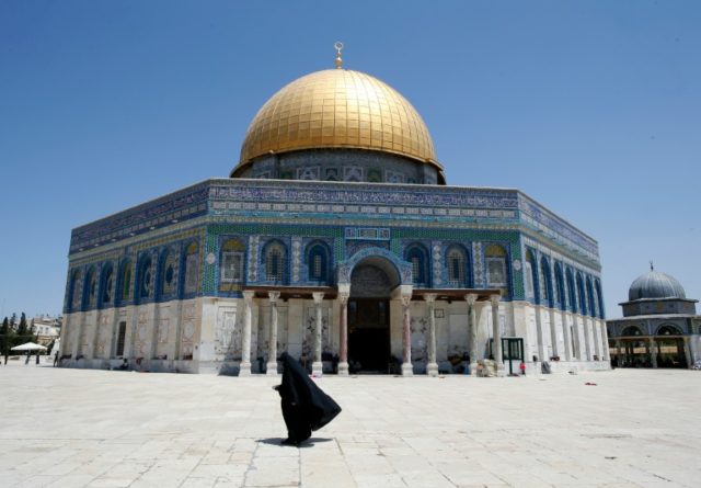 A Palestinian woman walks past the Dome of the Rock in Al-Aqsa Mosque compound in Jerusale