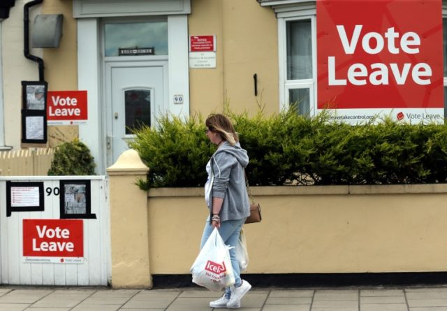 A woman walks past a house where "Vote Leave" boards are displayed in Redcar, north east E