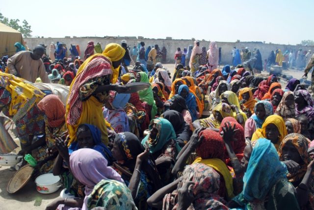 Internally displaced women and children sit waiting to be served with food at Dikwa Camp,