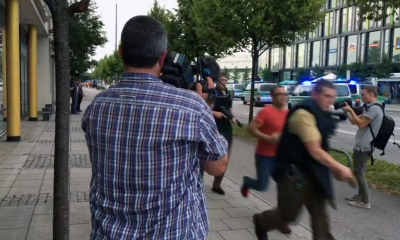 CORRECTS SOURCE Armed police move past onlooking media responding to a shooting at a shopping center in Munich, Germany, Friday July 22, 2016. Munich police confirm shots have been fired at Olympia Einkaufszentrum shopping center but say they don't have any details about casualties. Police are responding in large numbers. (AP)