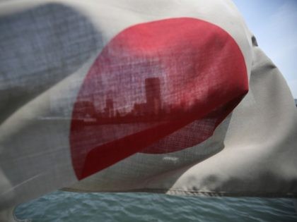 In this Wednesday, May 14, 2014 photo, buildings along the Sumida River are seen through a Japanese national flag fluttering on a sightseeing boat in Tokyo. Citing threats from China and North Korea, a government-appointed panel has urged Japan to reinterpret its pacifist constitution to allow the use of military …