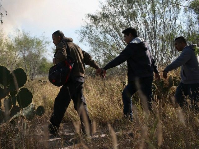 Immigrants walk handcuffed after illegally crossing the U.S.-Mexico border and being caugh