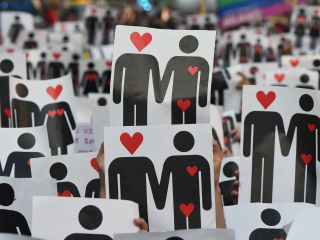 People hold placards depicting hearts and couples, during a flash mob for the annual Lesbian, Gay, Bisexual and Transgender (LGBT) Pride Parade in Milan, on June 25, 2016. / AFP / GIUSEPPE CACACE (Photo credit should read