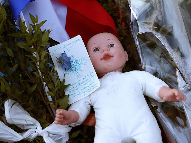 NICE, FRANCE - JULY 15: A childs doll sits next to a French flag and tributes to the vic