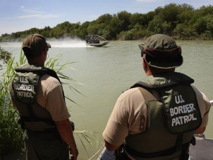 LAREDO, TX - AUGUST 07: U.S. Border Patrol agents watch colleagues motor past while patro