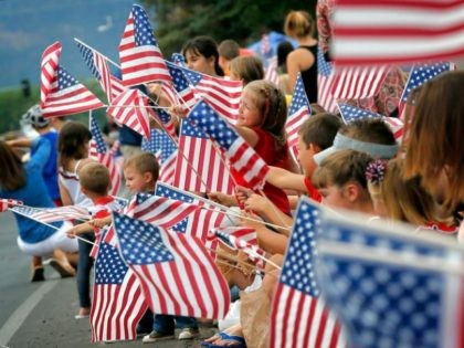 People wave flags as the Independence Day parade rolls down Main Street, Friday, July 4, 2