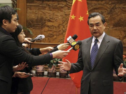 China's Foreign Minister Wang Yi (R) speaks to journalists in front of a Chinese national flag after a meeting with Japan's ambassador to China Masato Kitera (not seen), at the Ministry of Foreign Affairs in Beijing, December 26, 2013. China's Foreign Minister summoned Japan's ambassador to China on Thursday to …