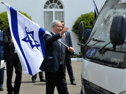 Israeli Prime Minister, Benjamin Netanyahu (L) holds an Israeli national flag after a join press conference with and Kenya's President in July 5, 2016 at the State House, in Nairobi. Netanyahu visits Kenya on the second leg of a four nation tour of sub-Saharan Africa. / AFP / SIMON MAINA …