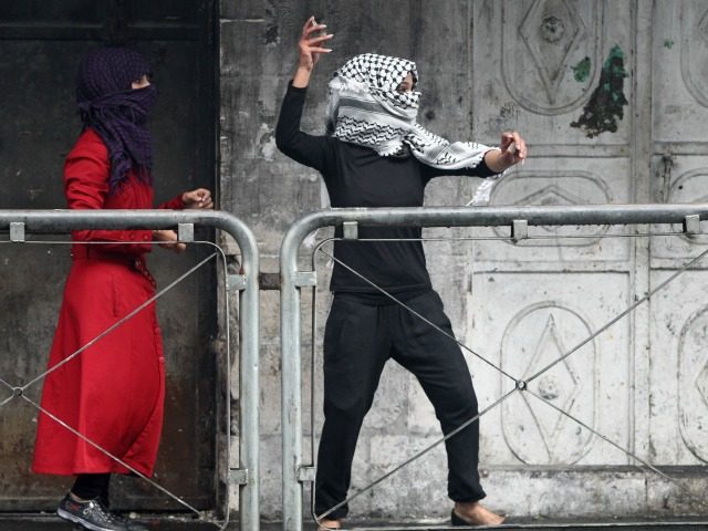 A Palestinian young woman throws stones towards Israeli security forces during clashes in