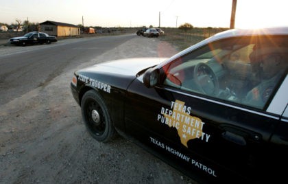 A Texas State Trooper is shown sitting in his vehicle right, as he and others maintain a roadblock miles from a religious retreat built by polygamist leader Warren Jeffs, Sunday, April 6, 2008, in Eldorado, Texas. (AP Photo/Tony Gutierrez)
