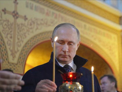 Russian President Vladimir Putin puts a candle in a hospital church while visiting the Dim