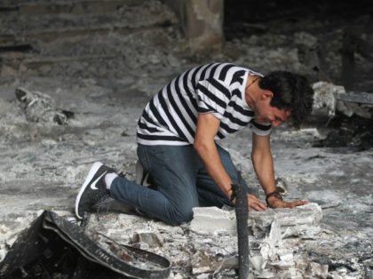 An Iraqi man reacts as he enters a building that was destroyed in a suicide-bombing attack