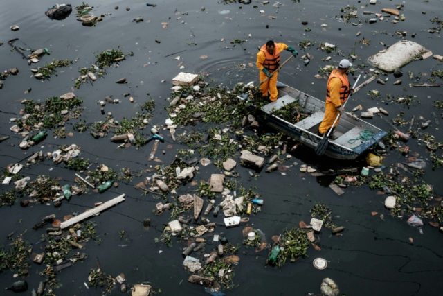 Cleaners clear up debris caught by the "eco-barrier" at Guanabara Bay near to Rio de Janei