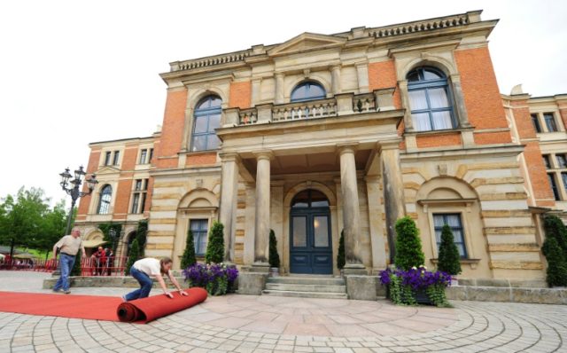 Workers roll out the red carpet in front of the festival house on the 'Green Hill' prior t