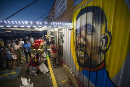 Protesters gather in front of a mural of Alton Sterling on the wall of a convenience store